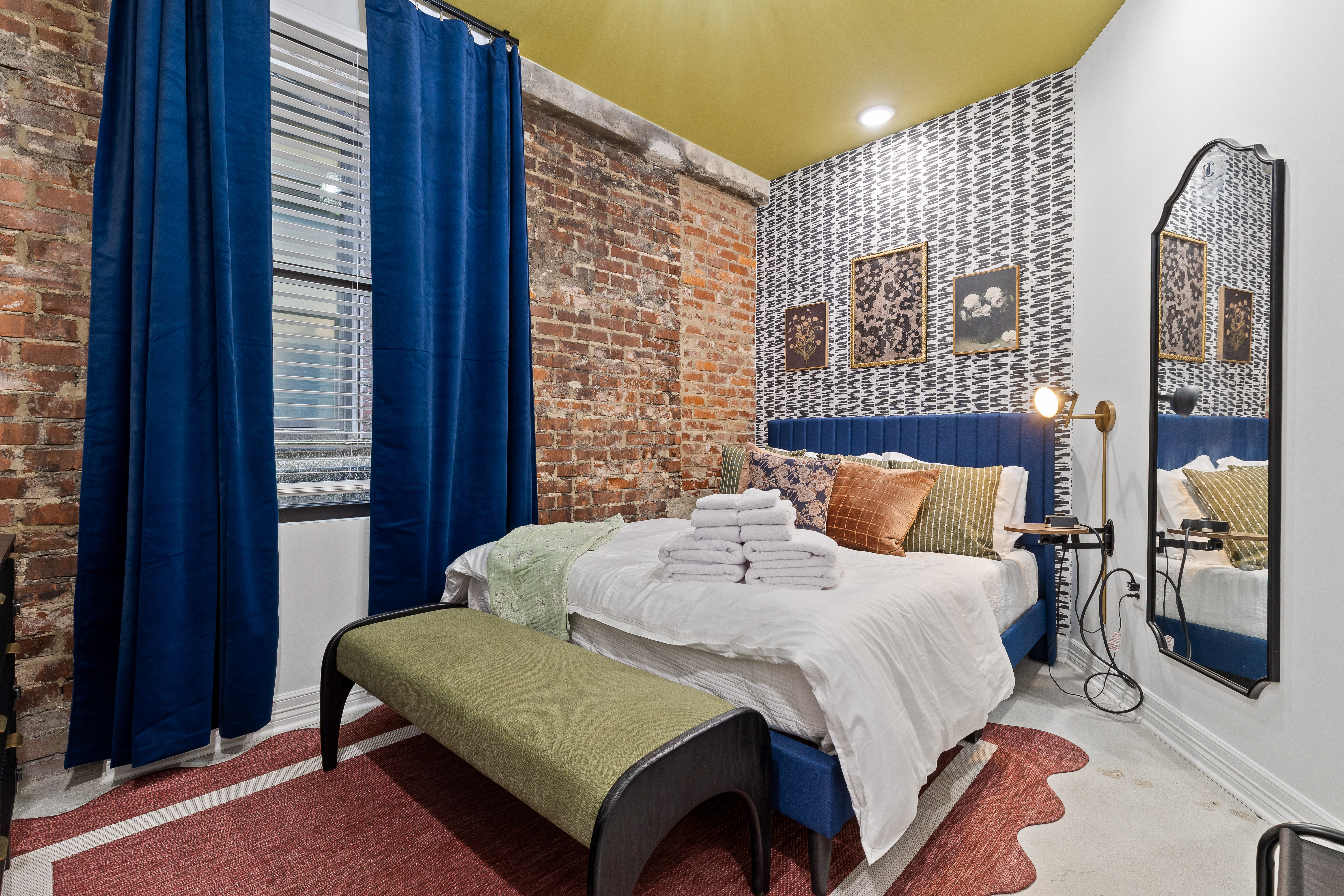Stylish brick-walled bedroom with plush blue bed and designer touches