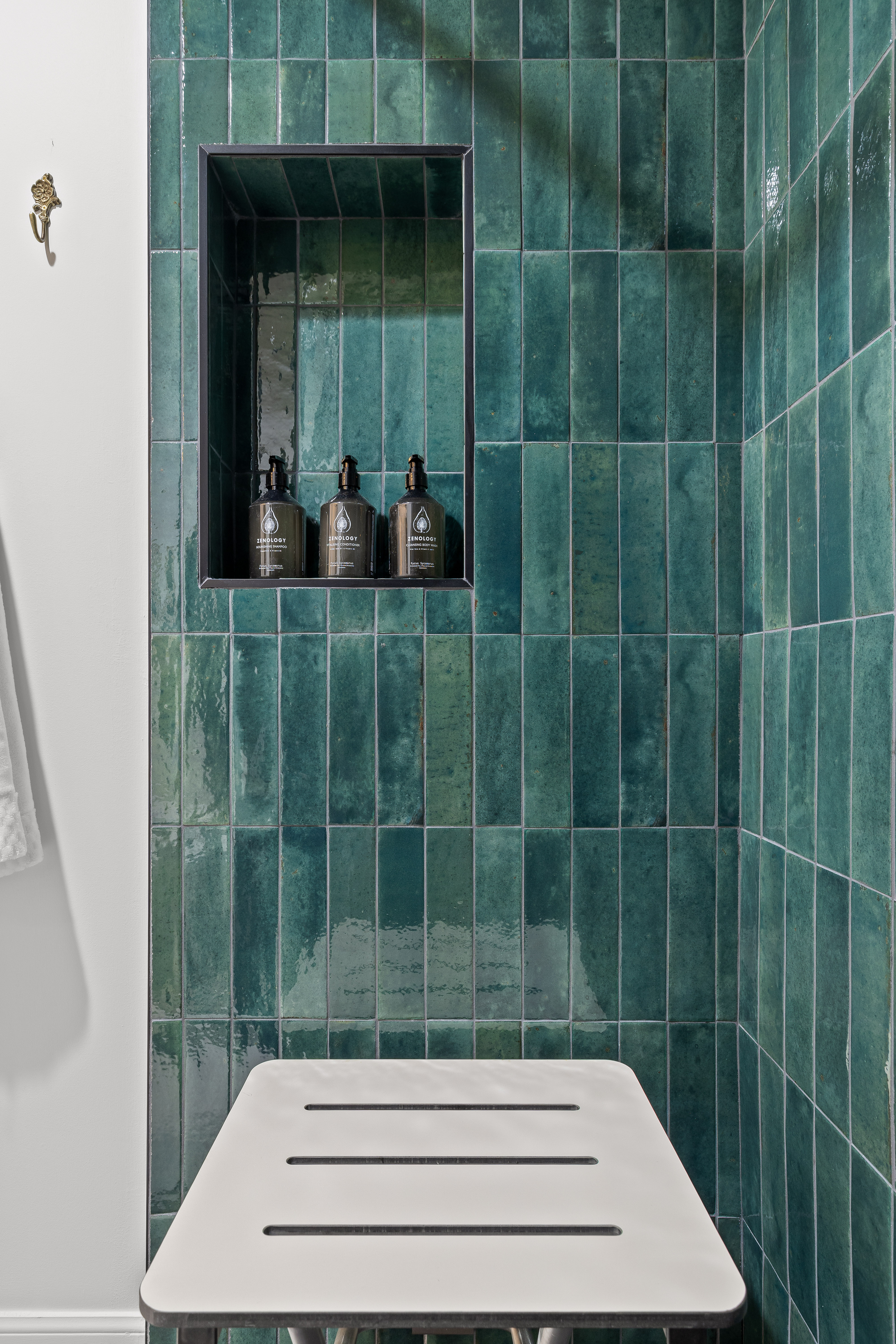 Spa-style shower with emerald tile, built-in niche, and sleek bench