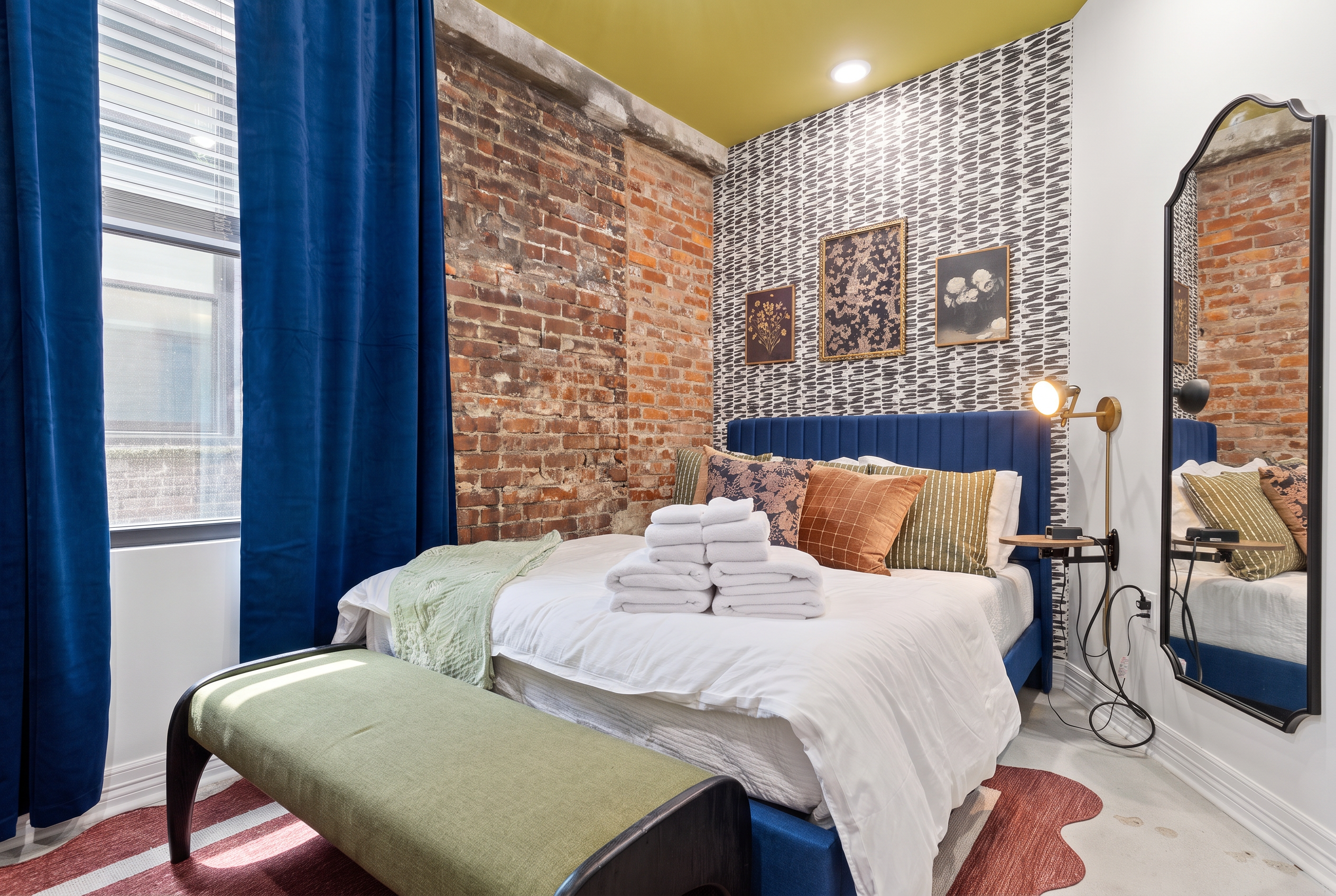 Chic brick-accent bedroom with bold decor, natural light, and cozy touches