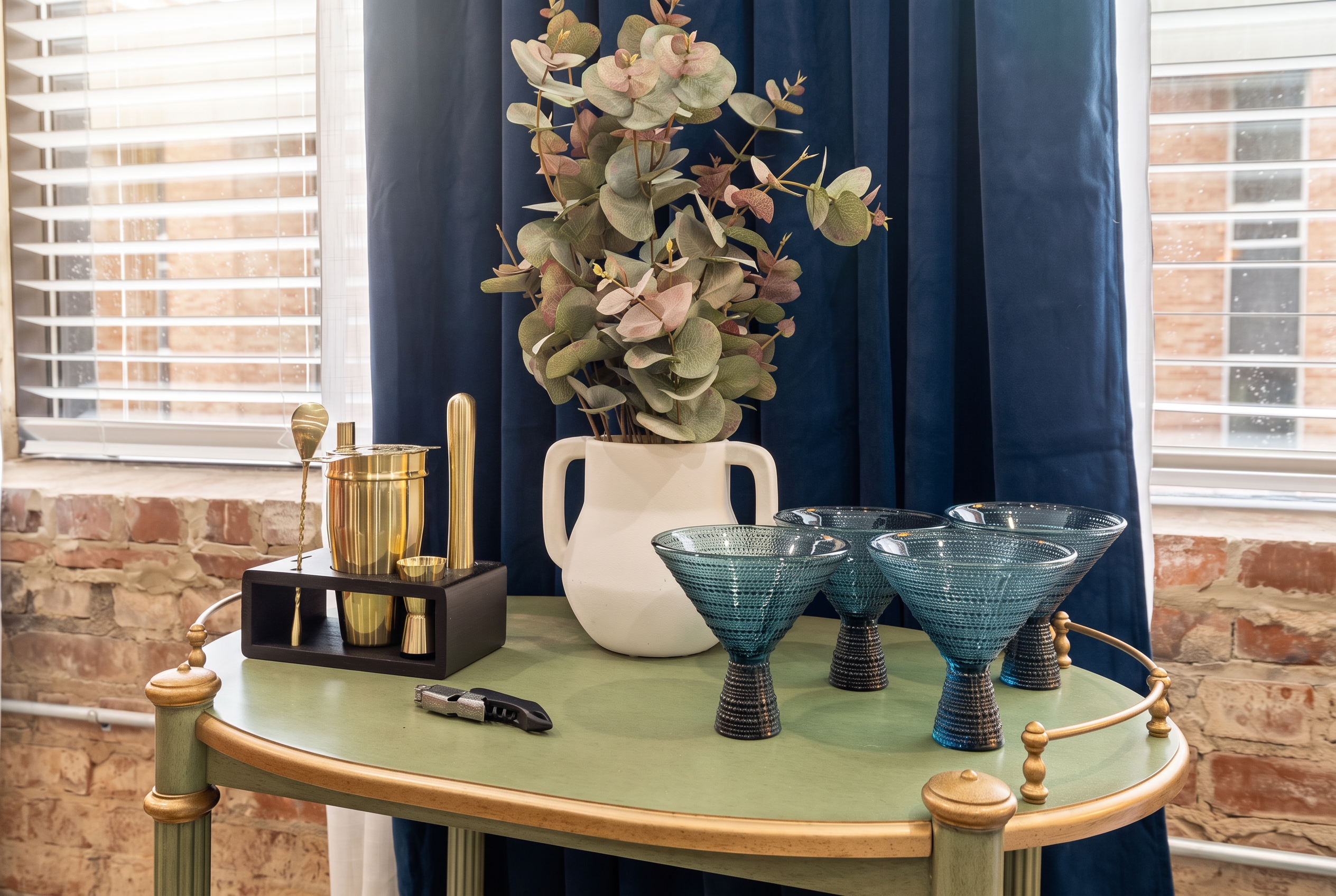 Stylish bar cart vignette with elegant glassware and charming brick backdrop