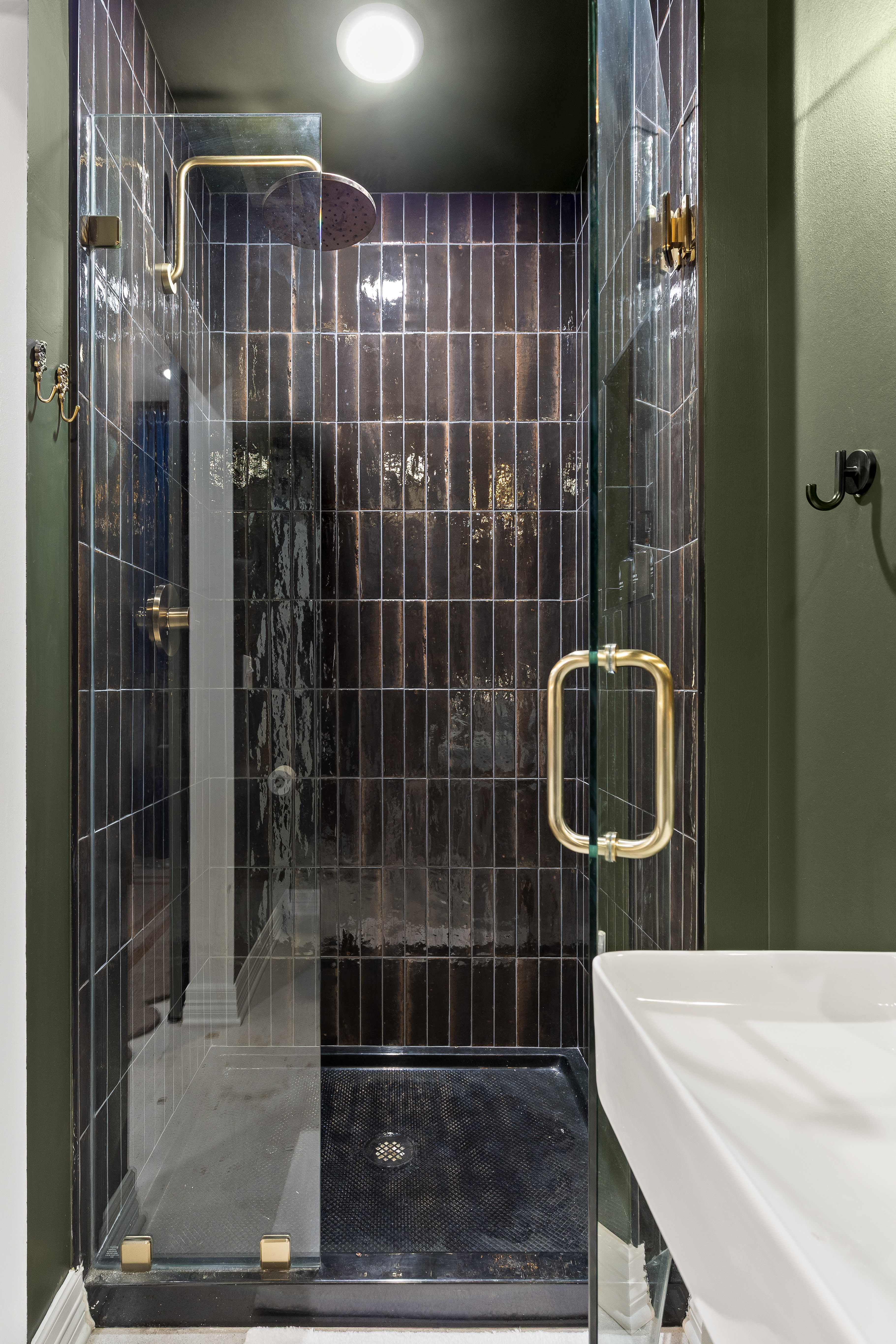 Stylish glass walk-in shower with brass accents and luxe dark tile