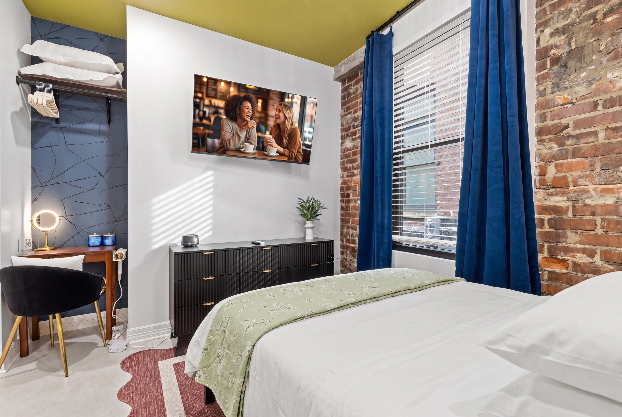 Cozy brick-walled bedroom with TV, natural light, and stylish work nook