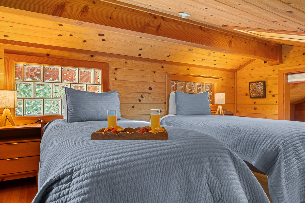 Cozy loft twin bedroom with warm wood and glass-block light—ideal for friends.