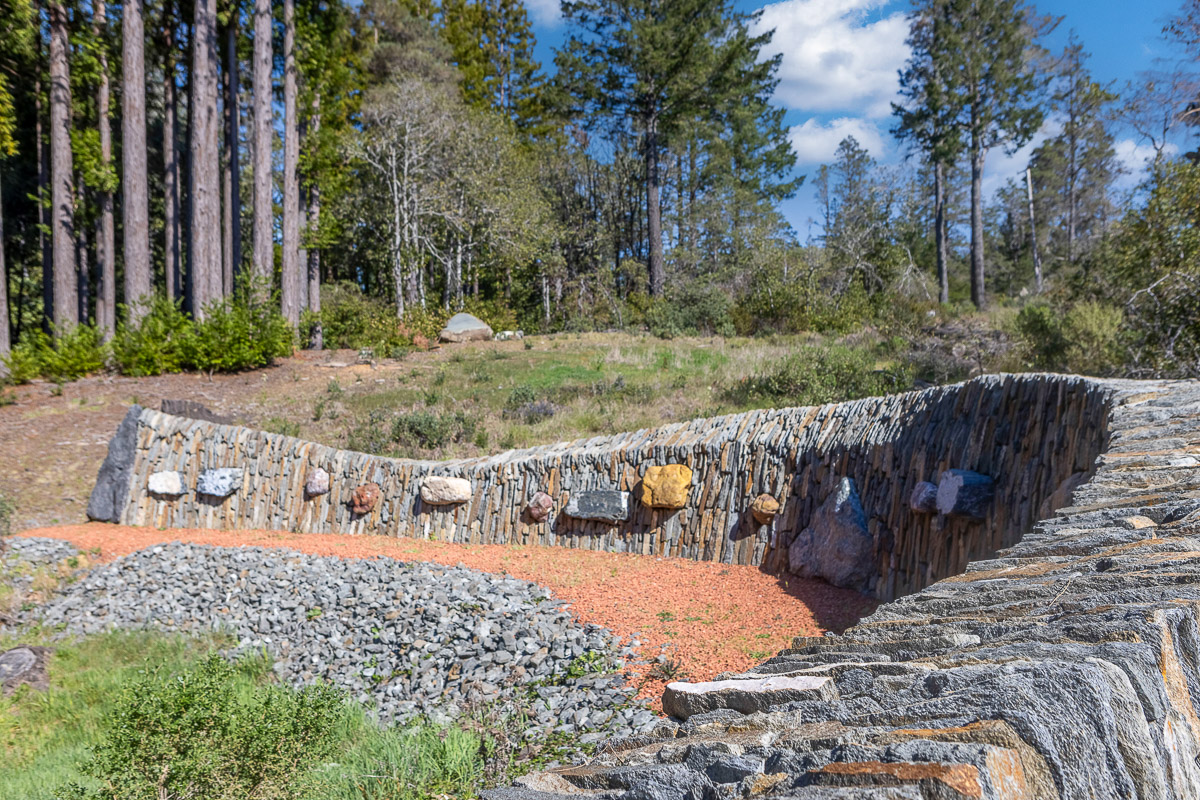 Curved stone wall and native gardens—peaceful forest-side retreat