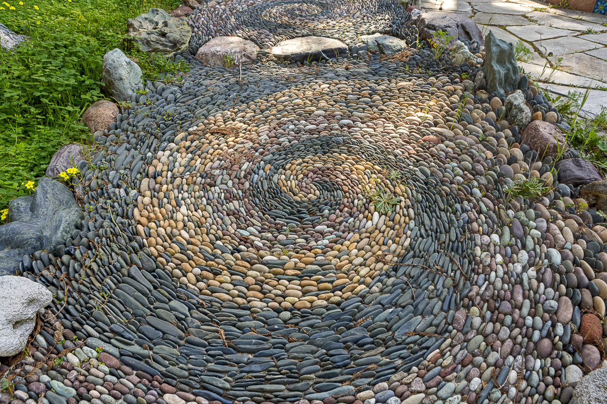 Artful Zen pebble spiral walkway leading to a tranquil garden patio