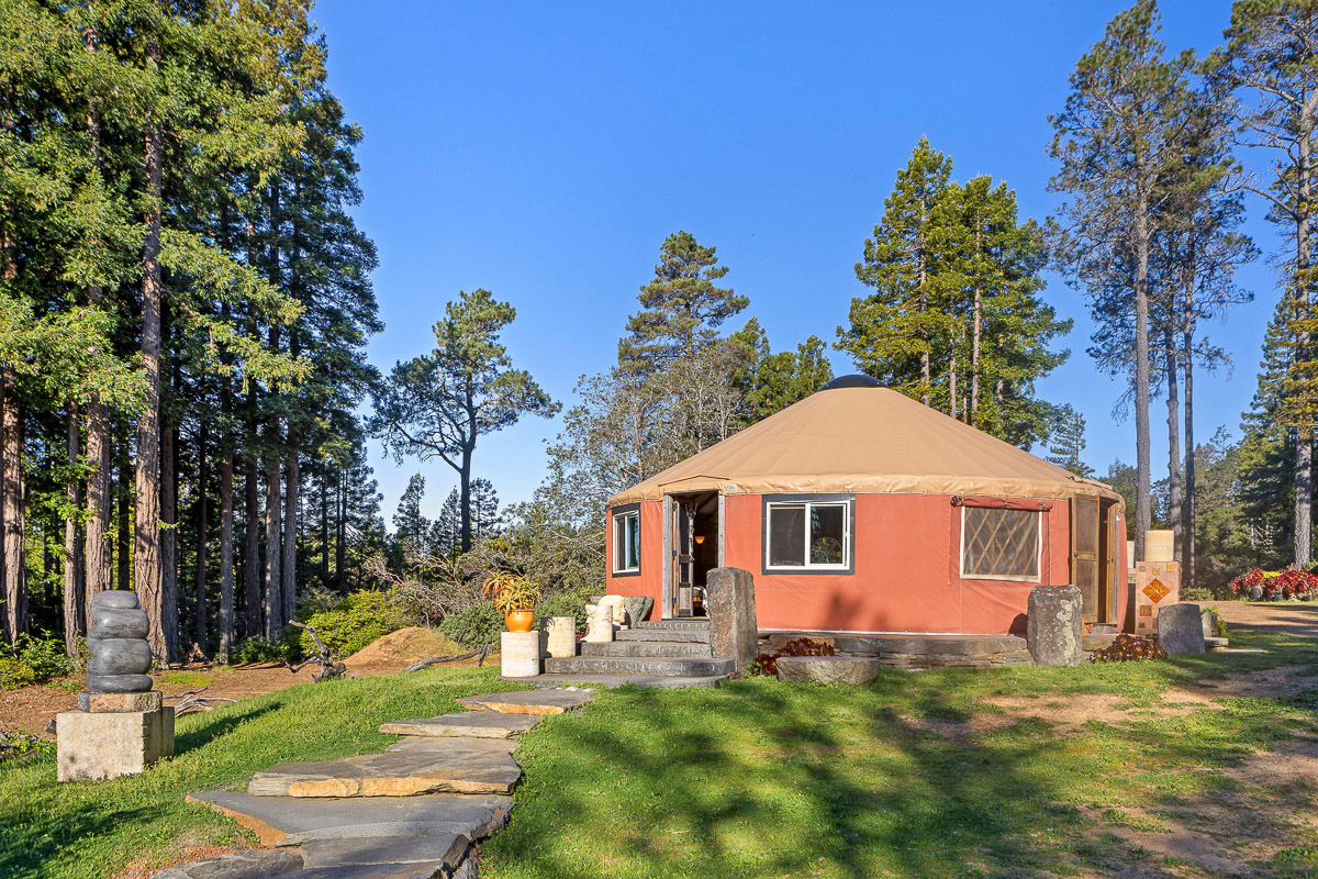 Secluded forest yurt with stone path, artful landscaping and sunshine