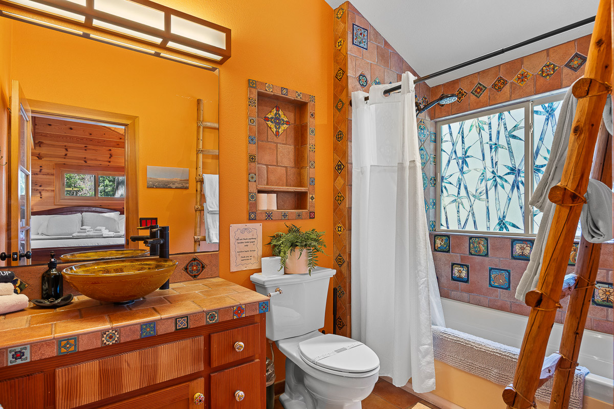 Vibrant tiled bath with vessel sink, sunny window, and tub/shower.