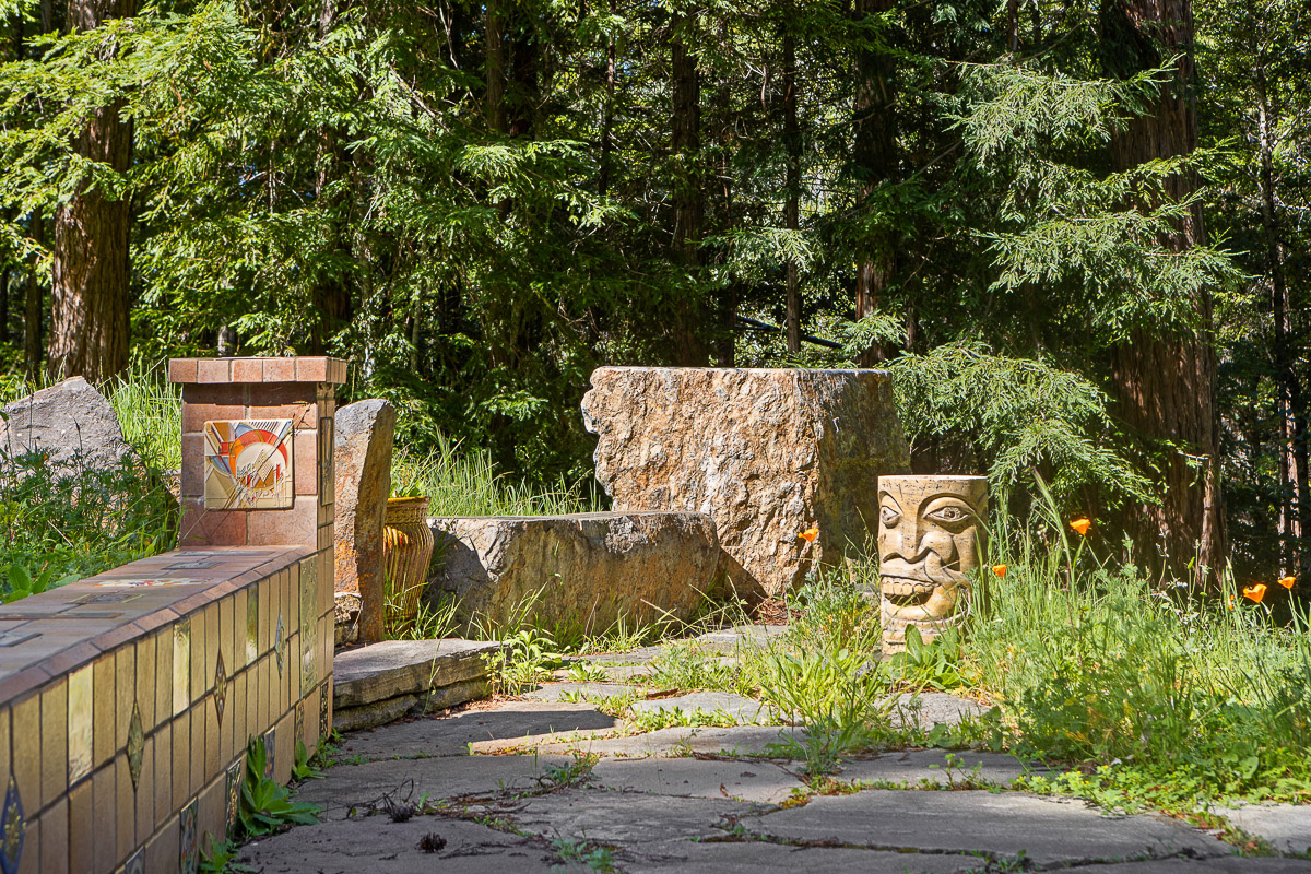 Tranquil forest patio with stone seating, mosaic tile and carvings