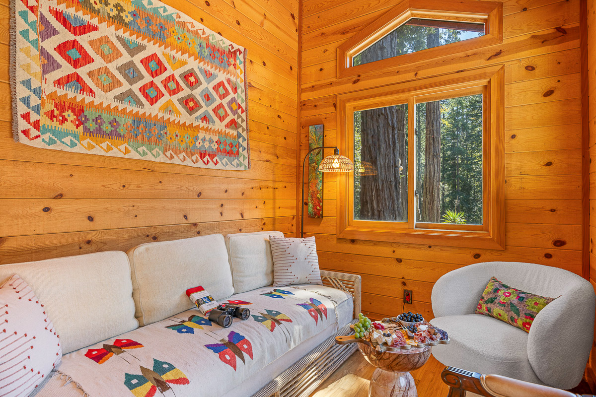 Sunny cabin lounge with forest views, artisan decor, and cozy seating.