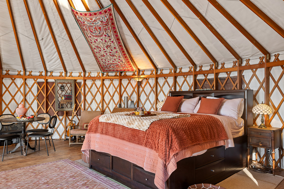 Cozy yurt retreat with plush queen bed, dining nook & skylight.