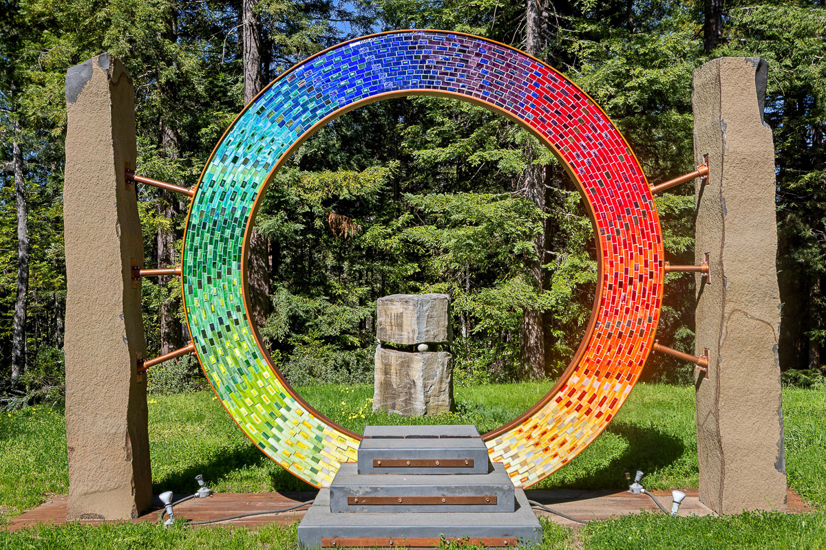 Colorful mosaic ring sculpture in a serene forest—ideal photo moment