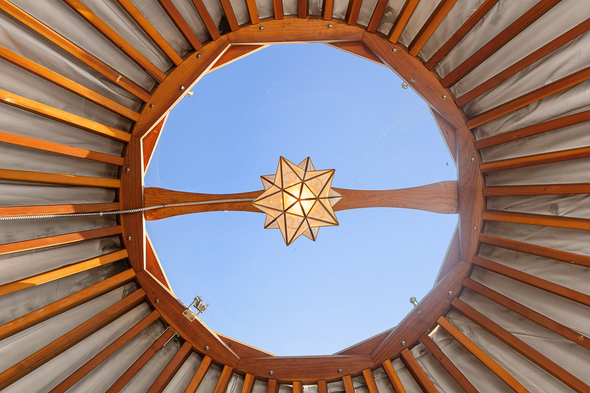 Yurt skylight with star pendant—sky views by day, stargazing by night.