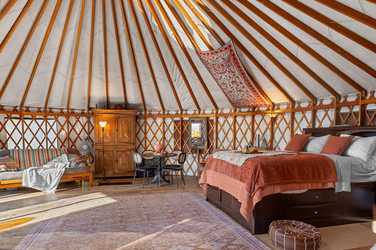 Cozy yurt retreat with plush bed, daybed, dining nook under soaring rafters
