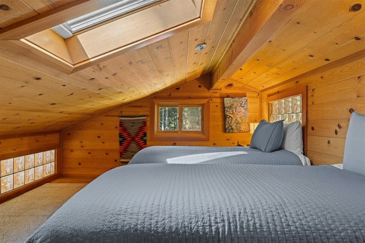 Sunny cabin loft with twin beds, skylight and rustic wood charm.