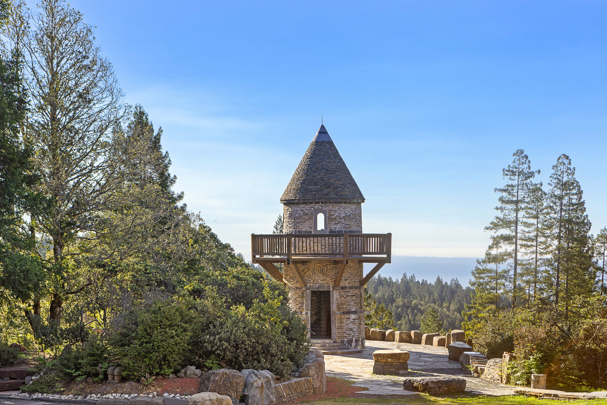 Storybook stone lookout with balcony and sweeping forest-to-sea views.