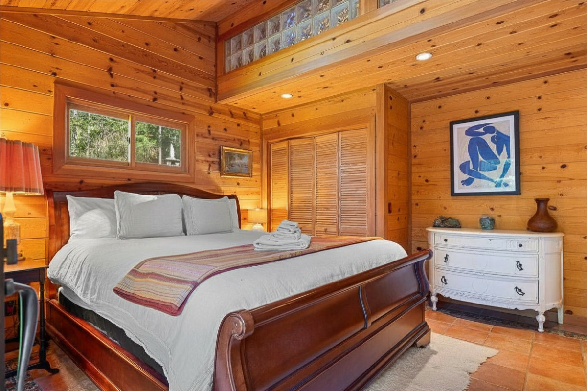 Cozy wood-paneled bedroom with king sleigh bed & warm natural light