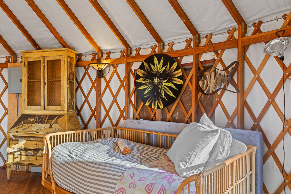 Cozy, art-filled yurt with daybed, vintage desk, and warm wood charm