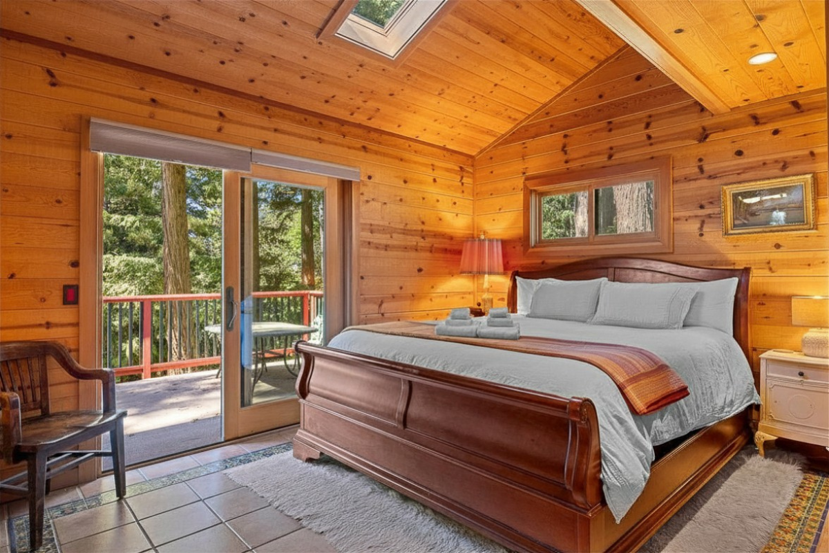 Cozy wood-clad king suite with skylight, deck, and forest views
