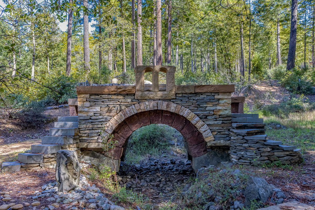 Charming stone footbridge over a forested creek—private trail escape