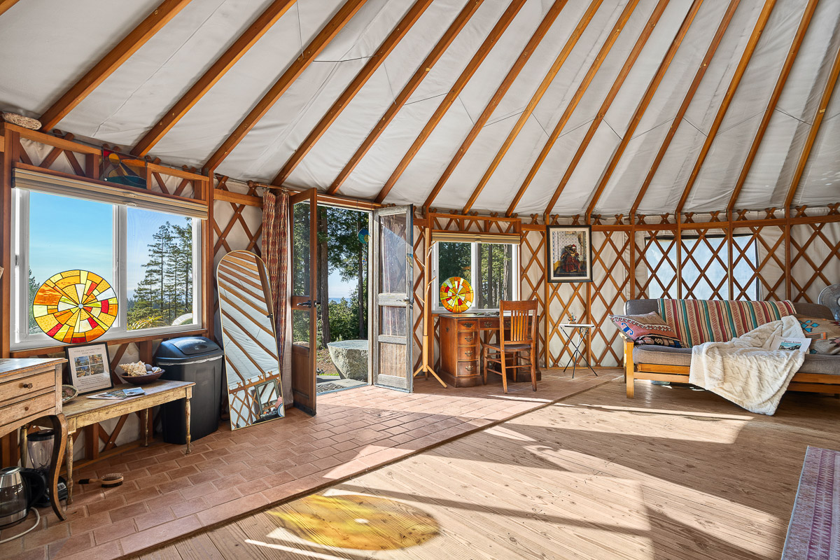 Sunny yurt with forest views, cozy daybed, and charming stained glass