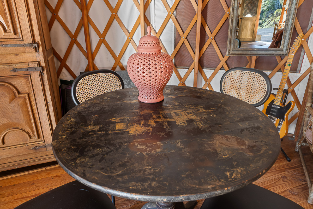 Eclectic yurt dining nook with vintage table, cane chairs & guitar.