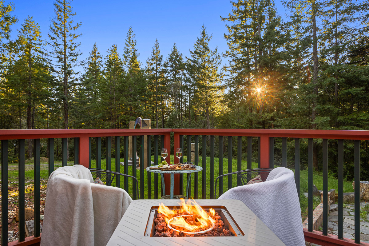 Cozy forest-view deck with fire pit, blankets, and sunset sips