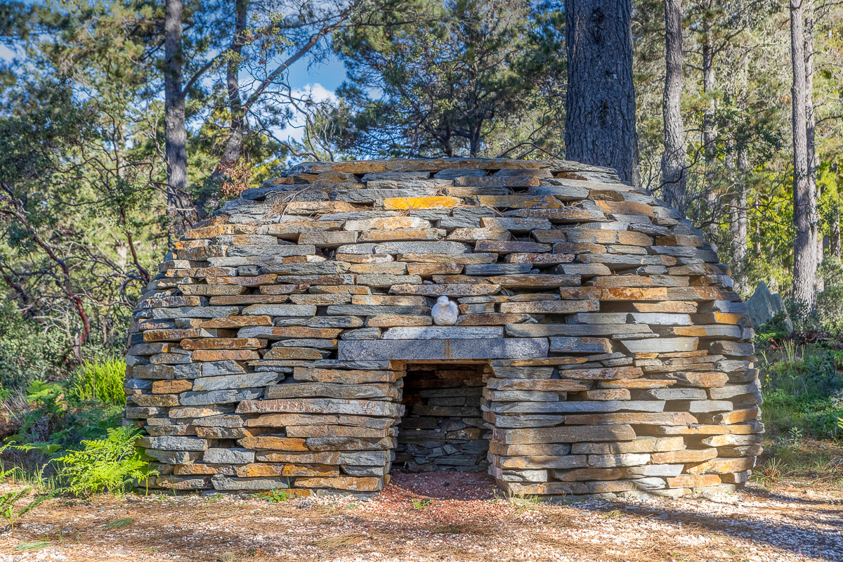 Rustic dry-stone dome in the pines—unique retreat nook and photo-worthy gem.