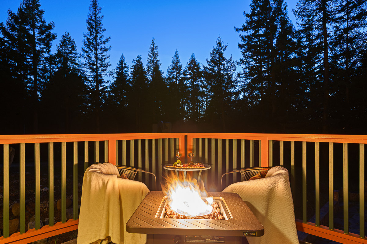 Cozy deck with fire pit, blankets, and forest views—ideal for stargazing