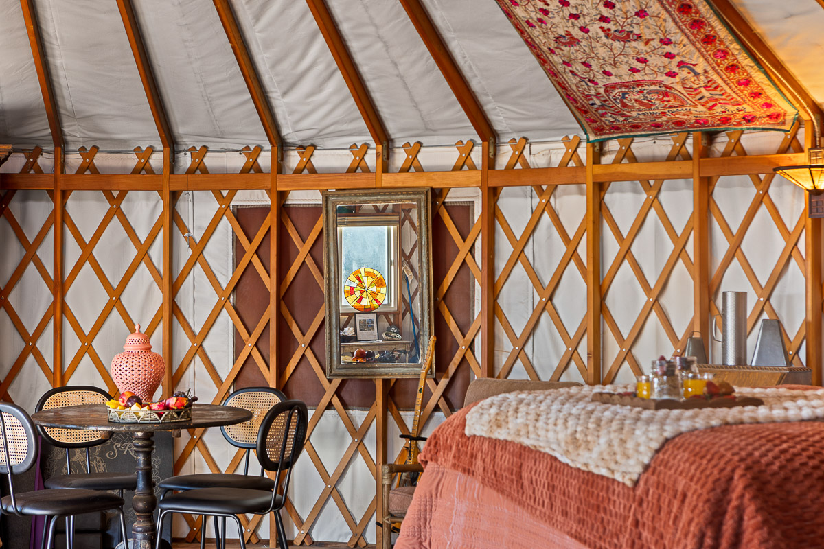 Cozy yurt with plush bed, bistro table & boho decor—glamp in style