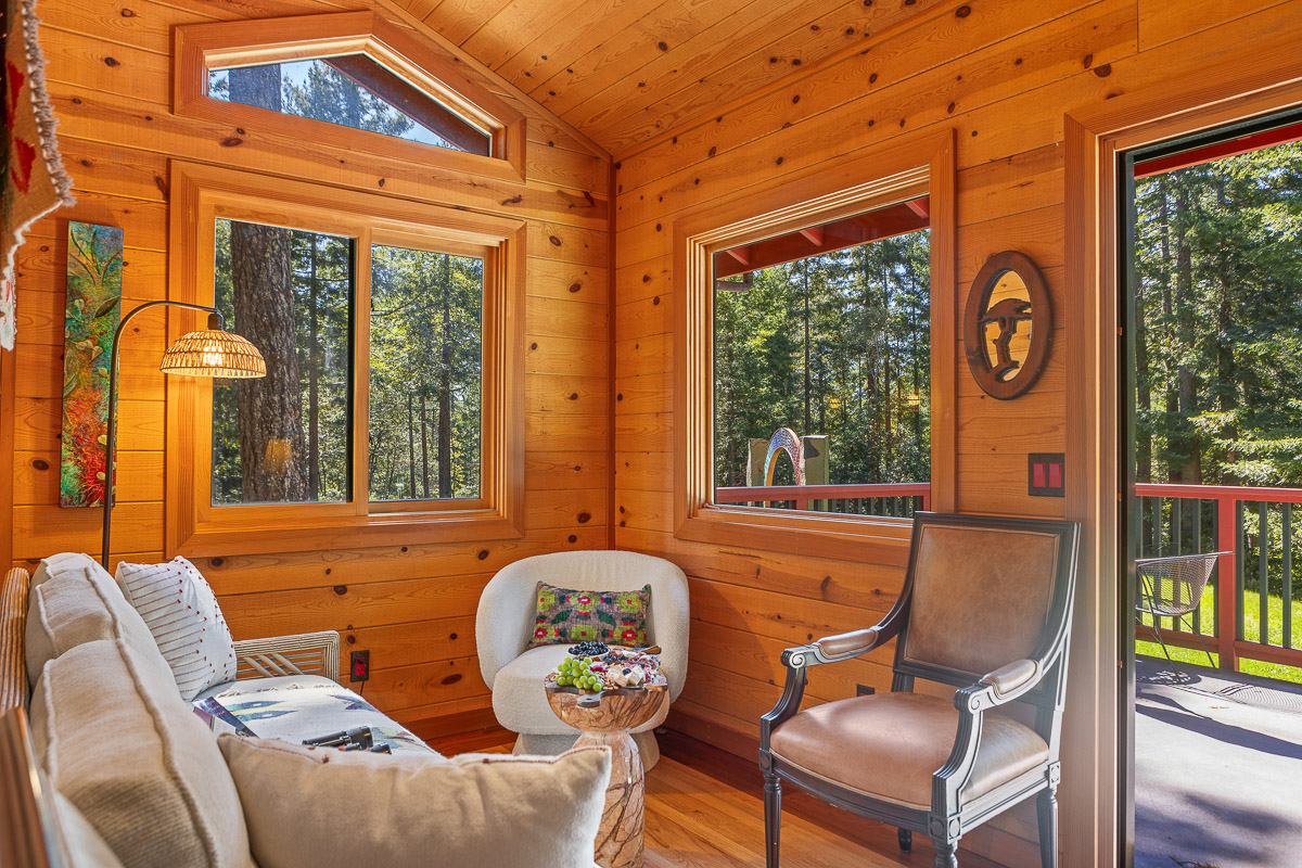 Sunlit cabin lounge with forest views and deck access