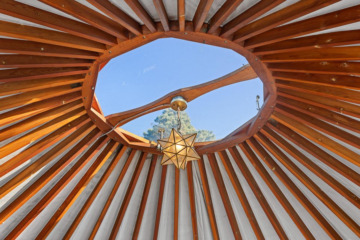 Yurt with oculus skylight and star pendant—bright, cozy, stargazer’s nook.