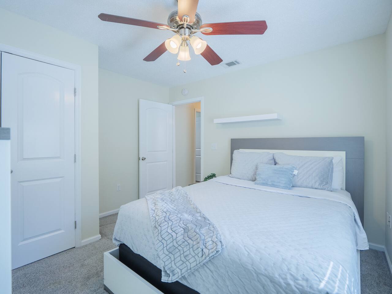 Second bedroom with white platform bed and blue accent pillows