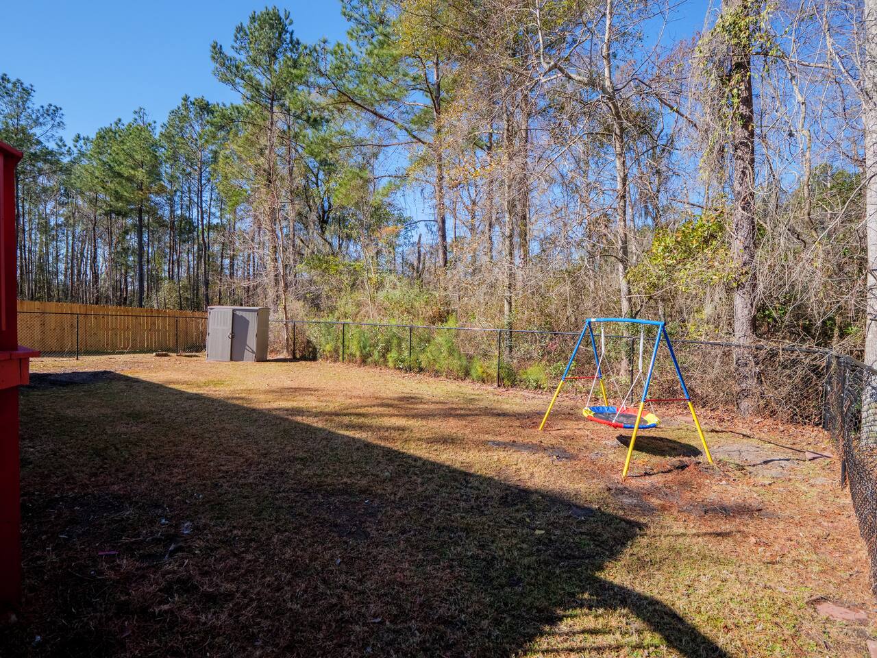 Fenced backyard bordered by pines
