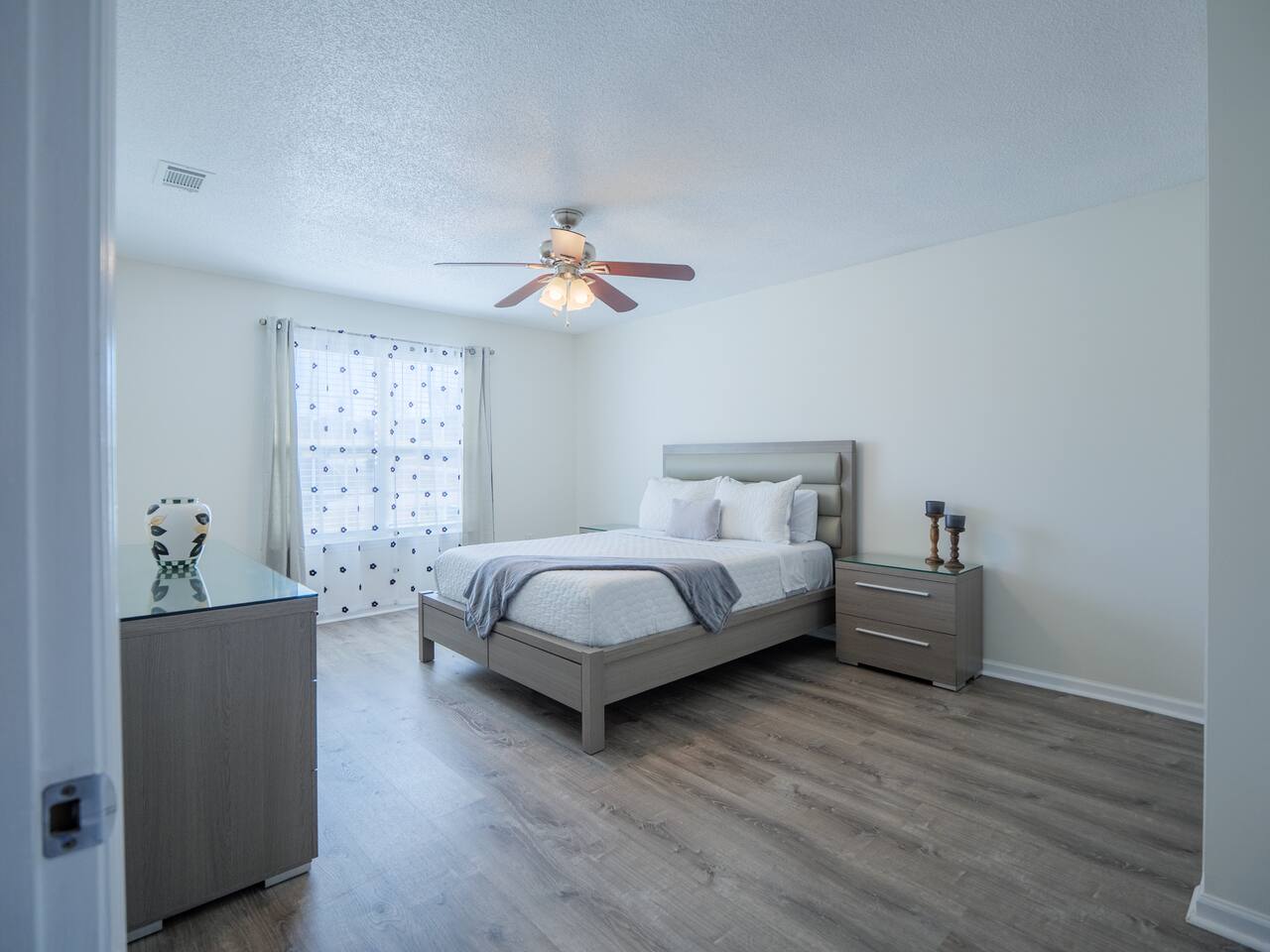 Primary bedroom with queen bed and gray upholstered headboard
