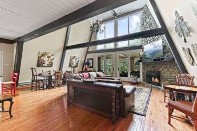 Step inside to soaring ceilings, exposed beams, and an open concept living area anchored by a fireplace. Designed for gathering, this space blends comfort, charm, and cabin elegance.