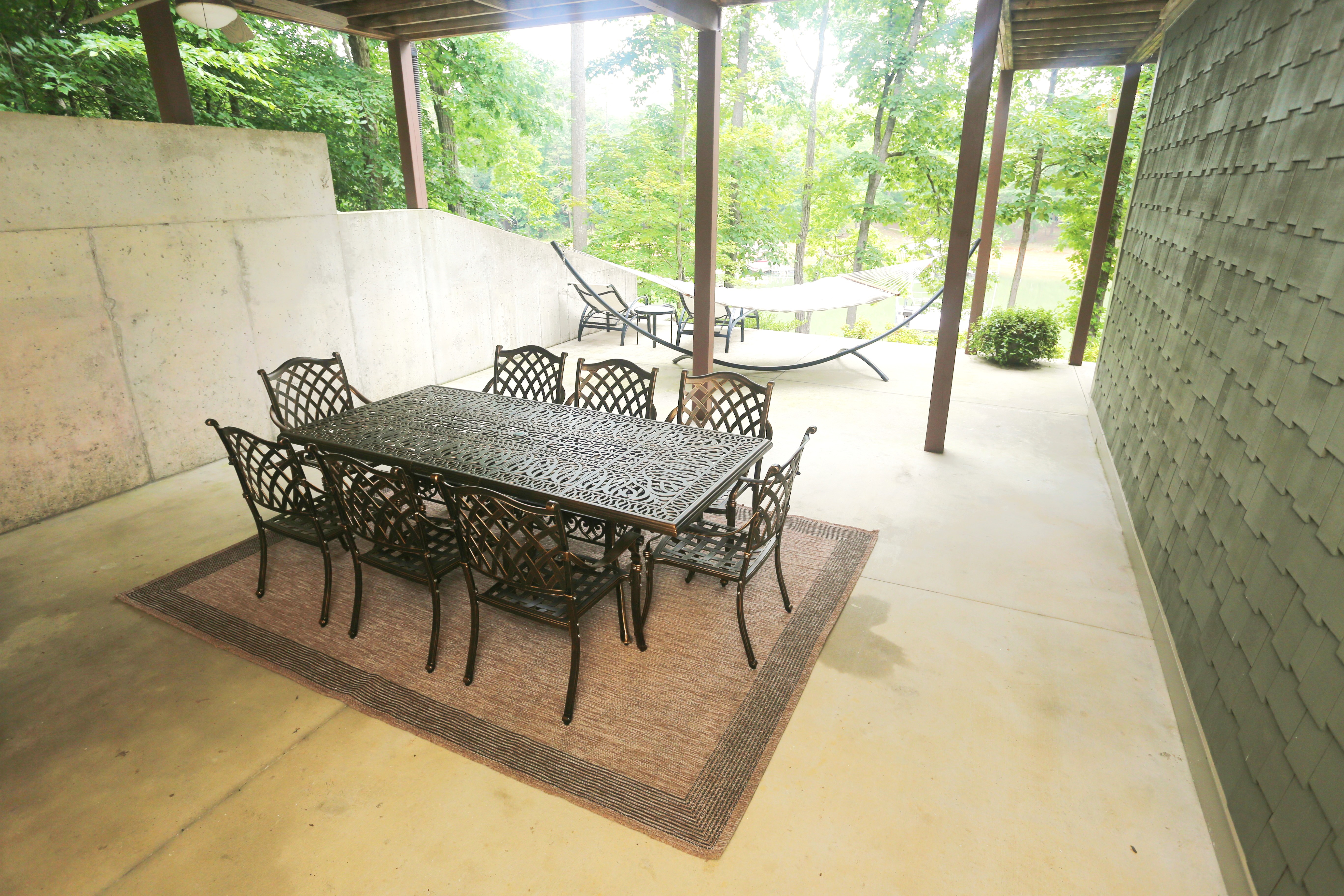 Covered patio with outdoor dining, hammock, and peaceful wooded views