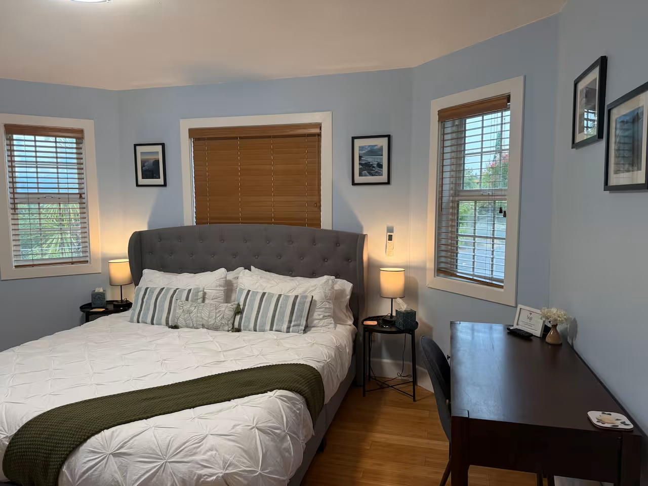 Calm, light-filled bedroom with king bed, desk workspace, and cozy lamps.