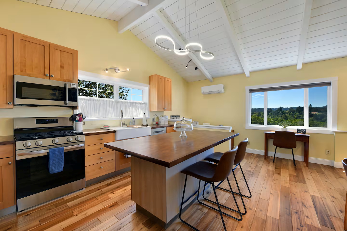 Sunny chef’s kitchen with island, farmhouse sink, hill views & workspace