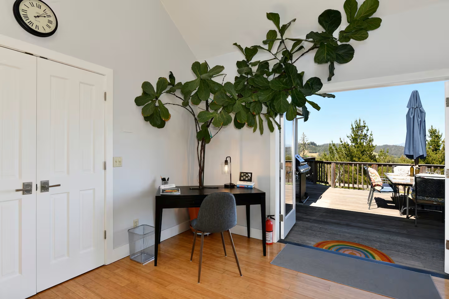 Sunny home office opens to view deck with seating and grill-ready space
