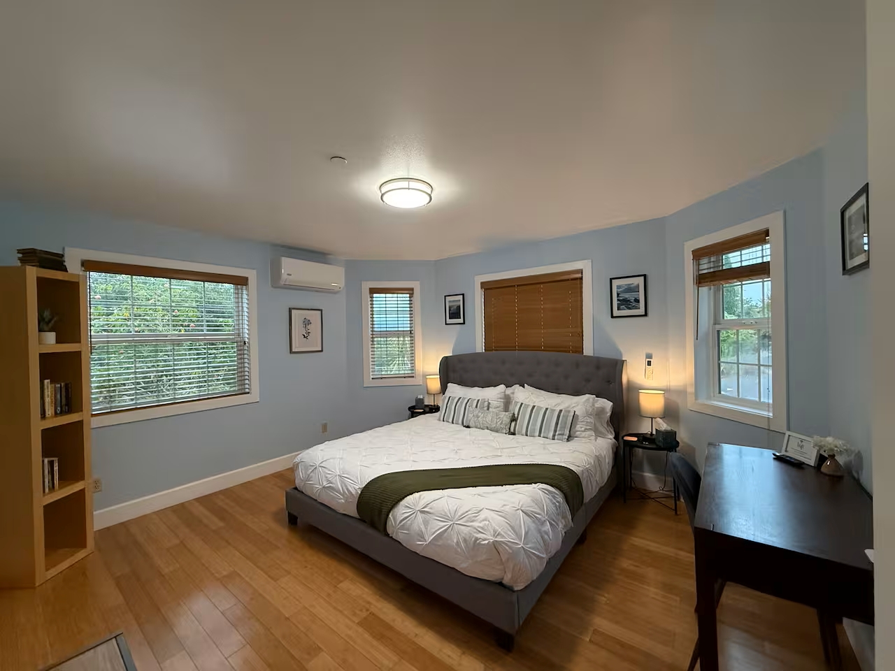 Serene king bedroom with desk, A/C, hardwood floors, bright windows.