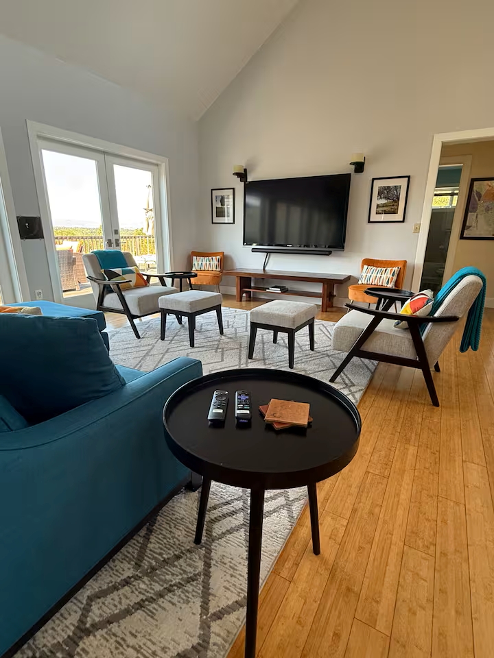 Sunny lounge with big-screen TV, mid-century seating, deck access & views