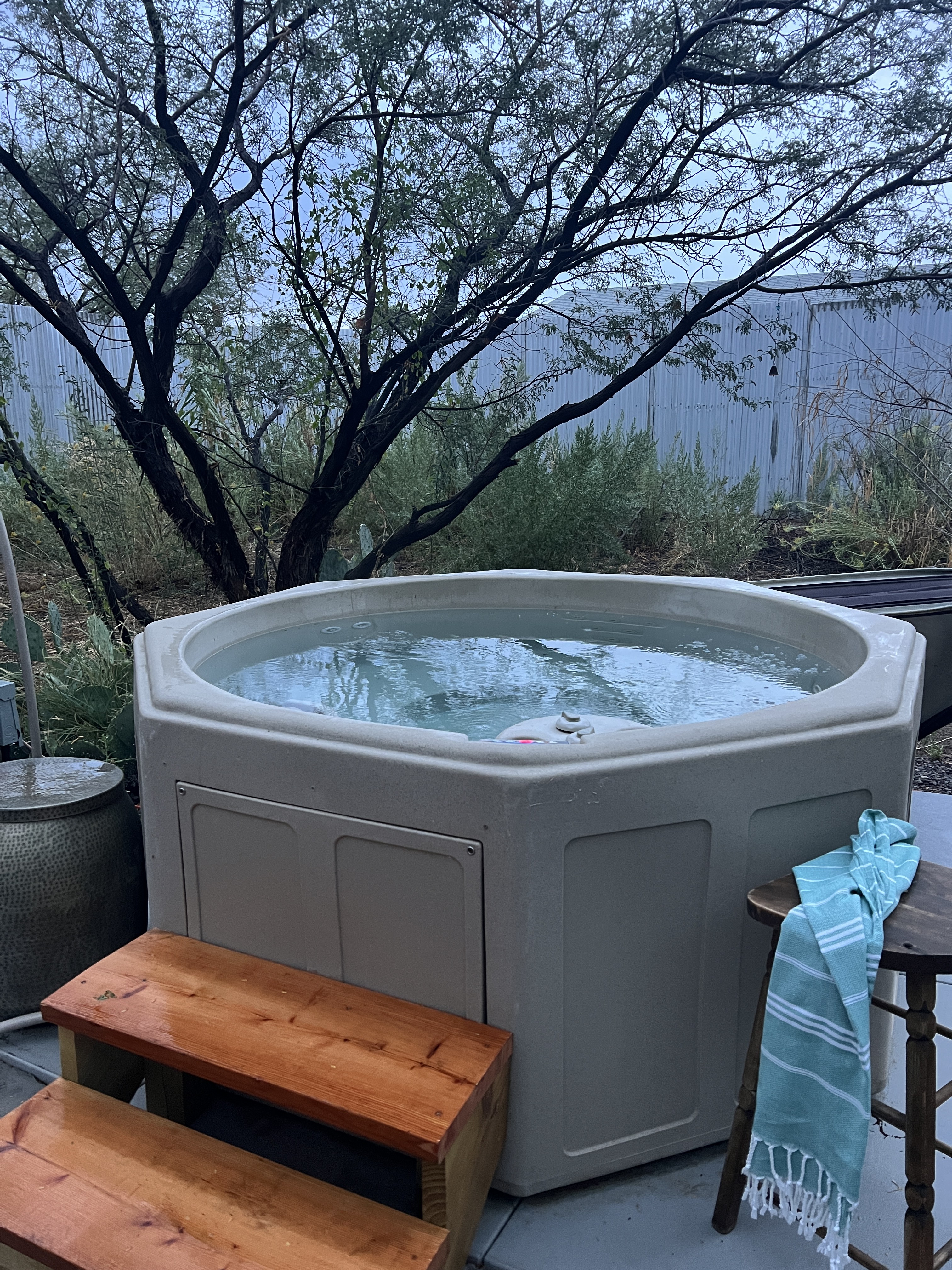 Private outdoor hot tub with serene trees and a cozy, spa-like setup