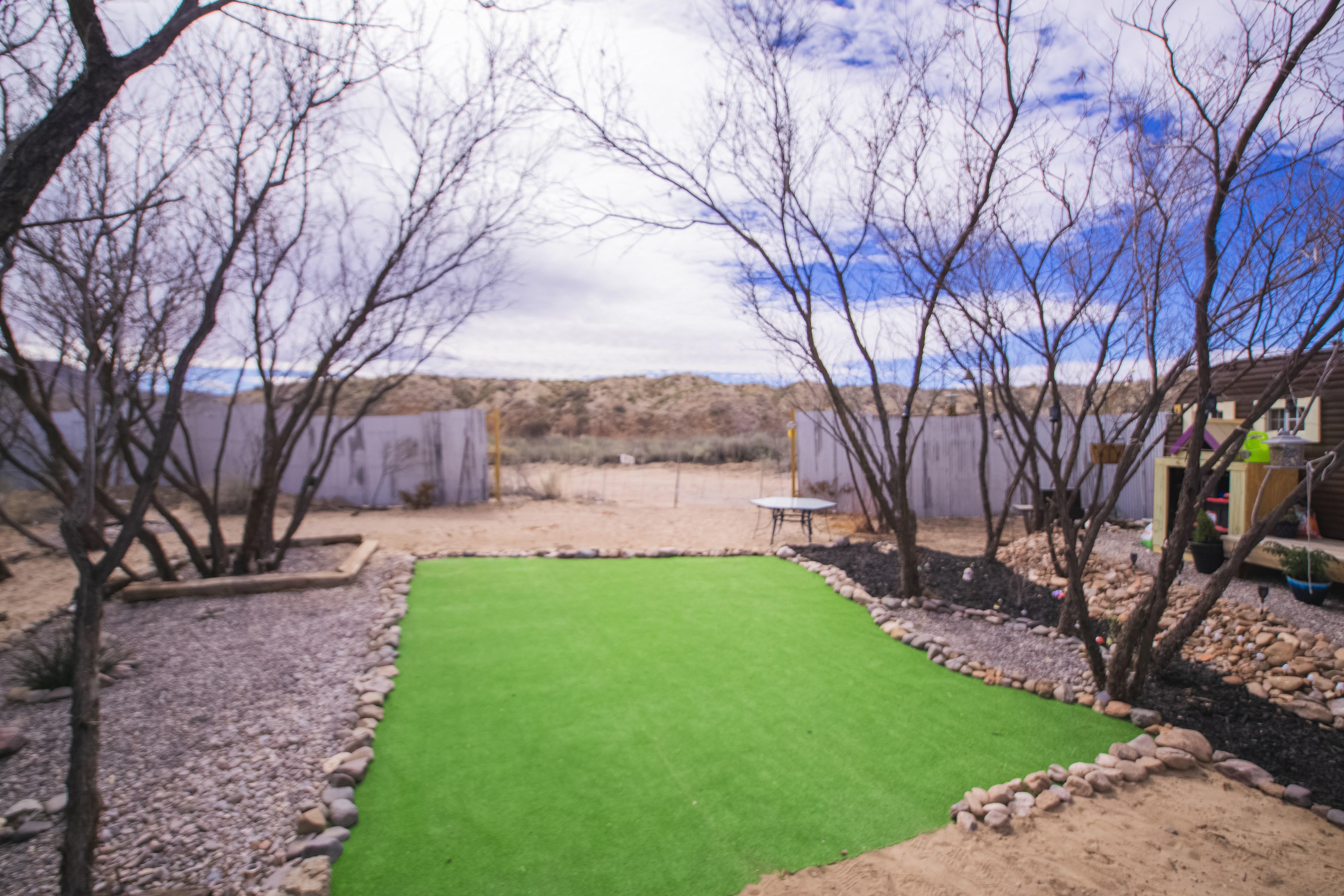 Private desert yard with turf lawn, shade trees, and open scenic views