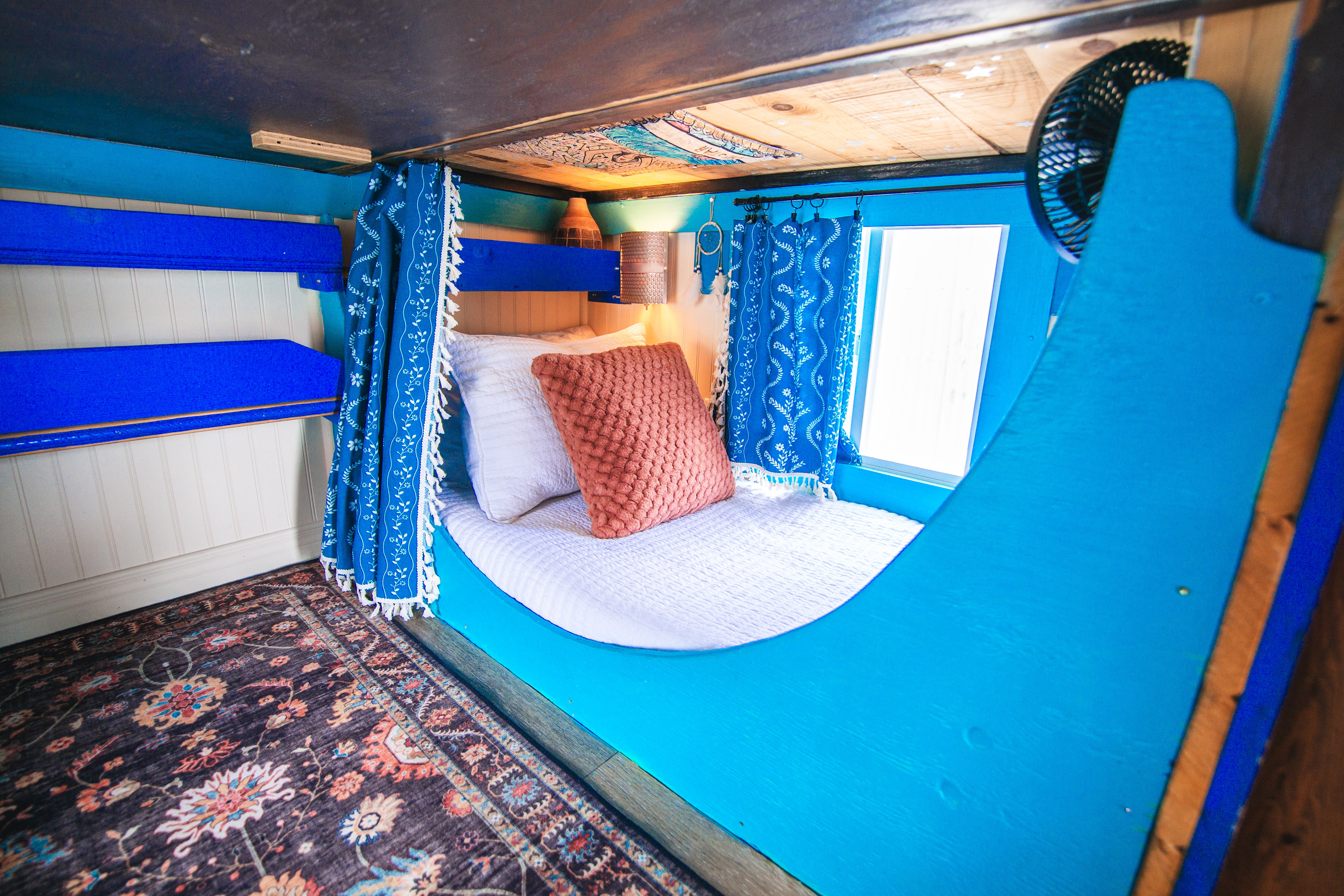 Cozy blue built-in bunk nook with charming decor and natural light