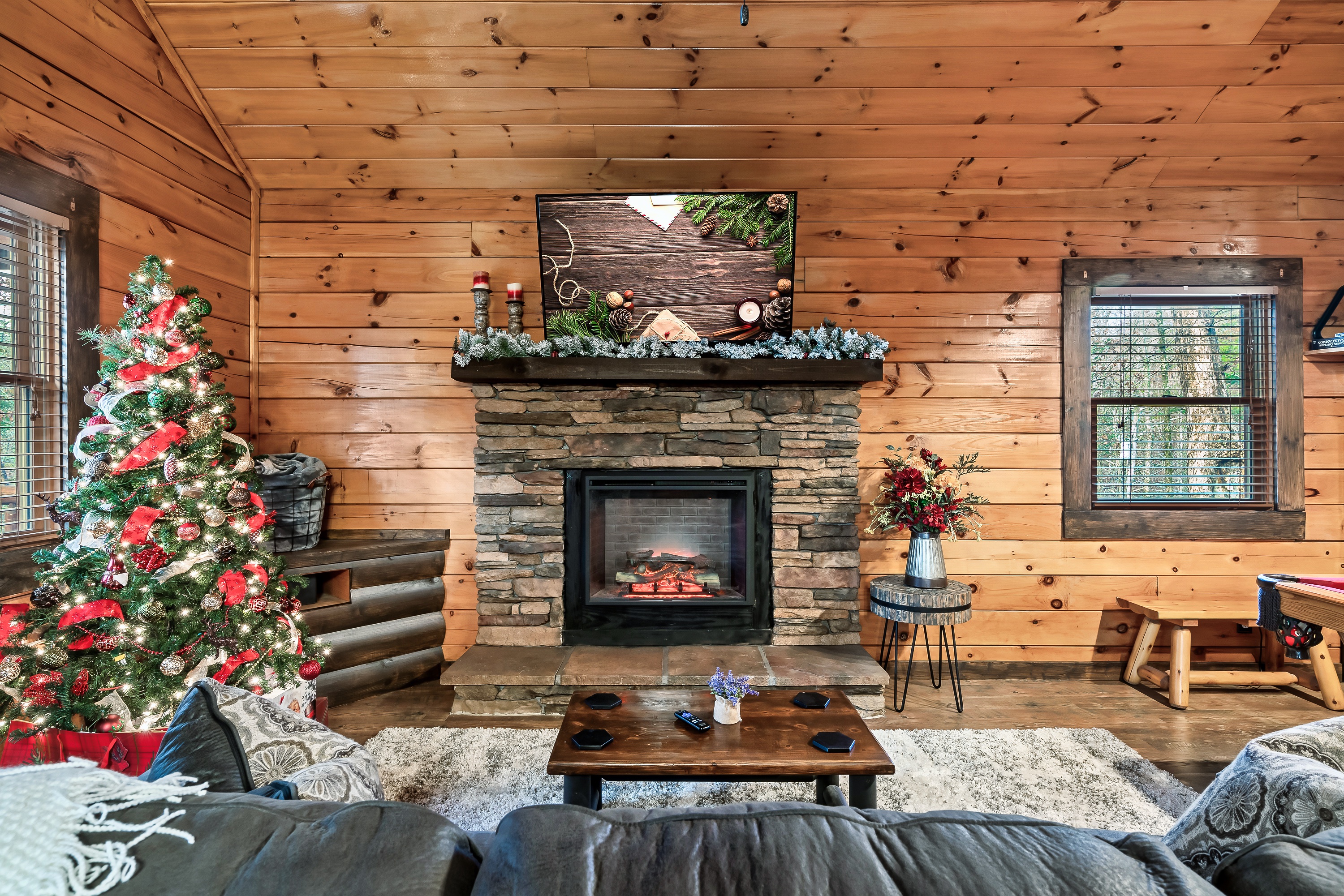 Garland-draped stone mantel with a glowing fireplace, all decked out for the holidays