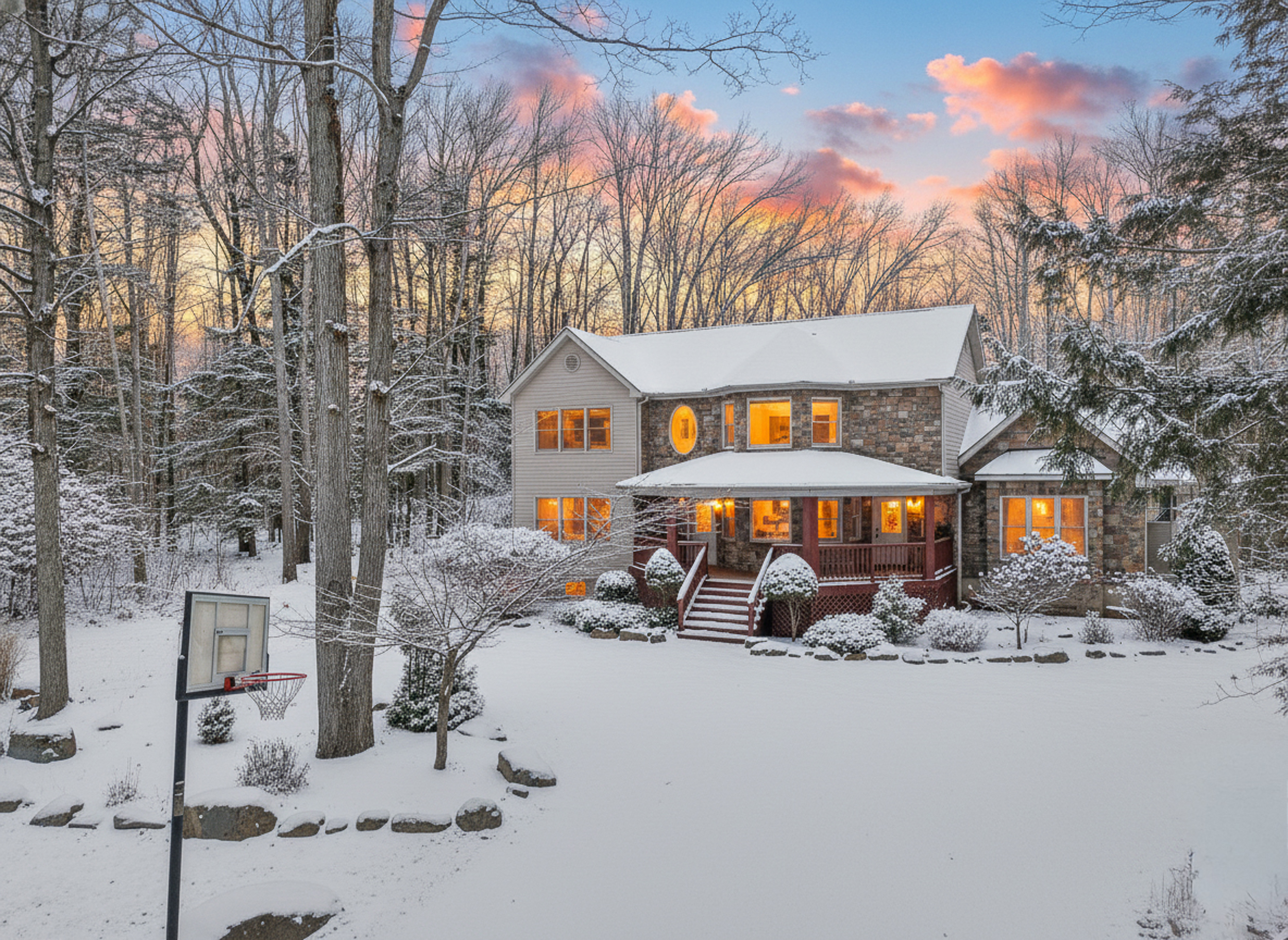 Cozy snowy retreat with glowing windows and peaceful wooded views