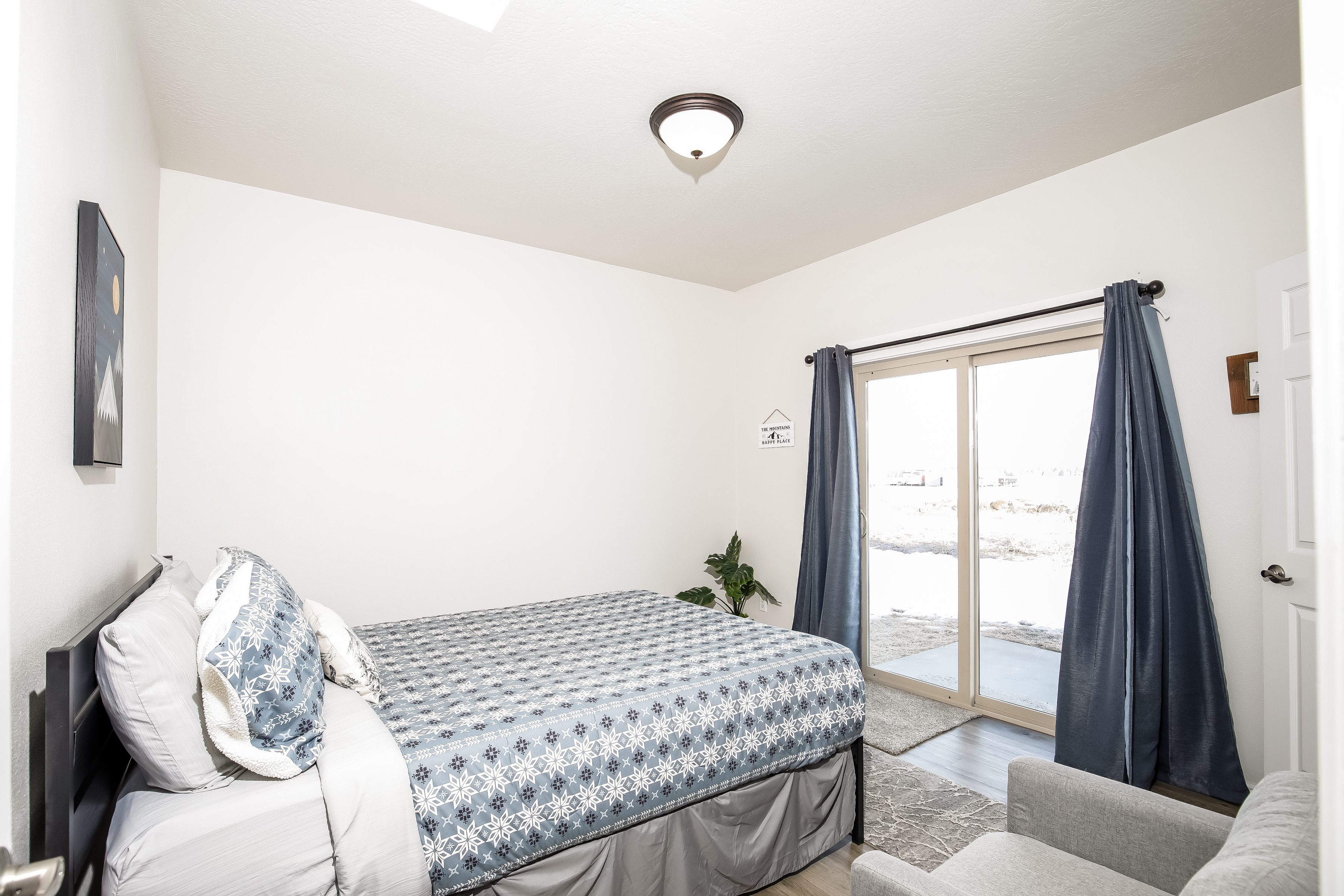 Bright bedroom with patio access, queen bed, and blackout drapes.