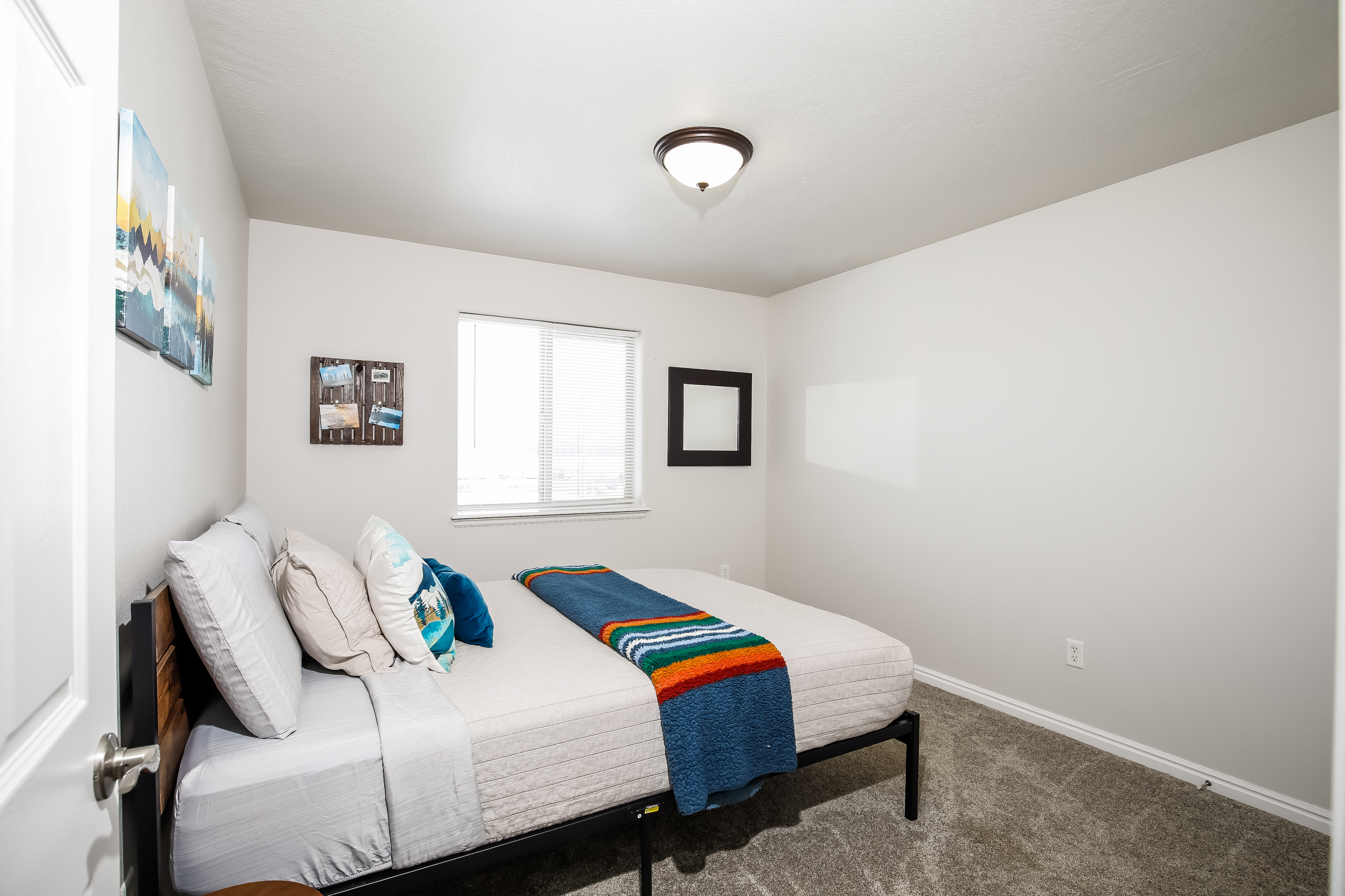 Bright, cozy bedroom with queen bed, plush carpet, and natural light