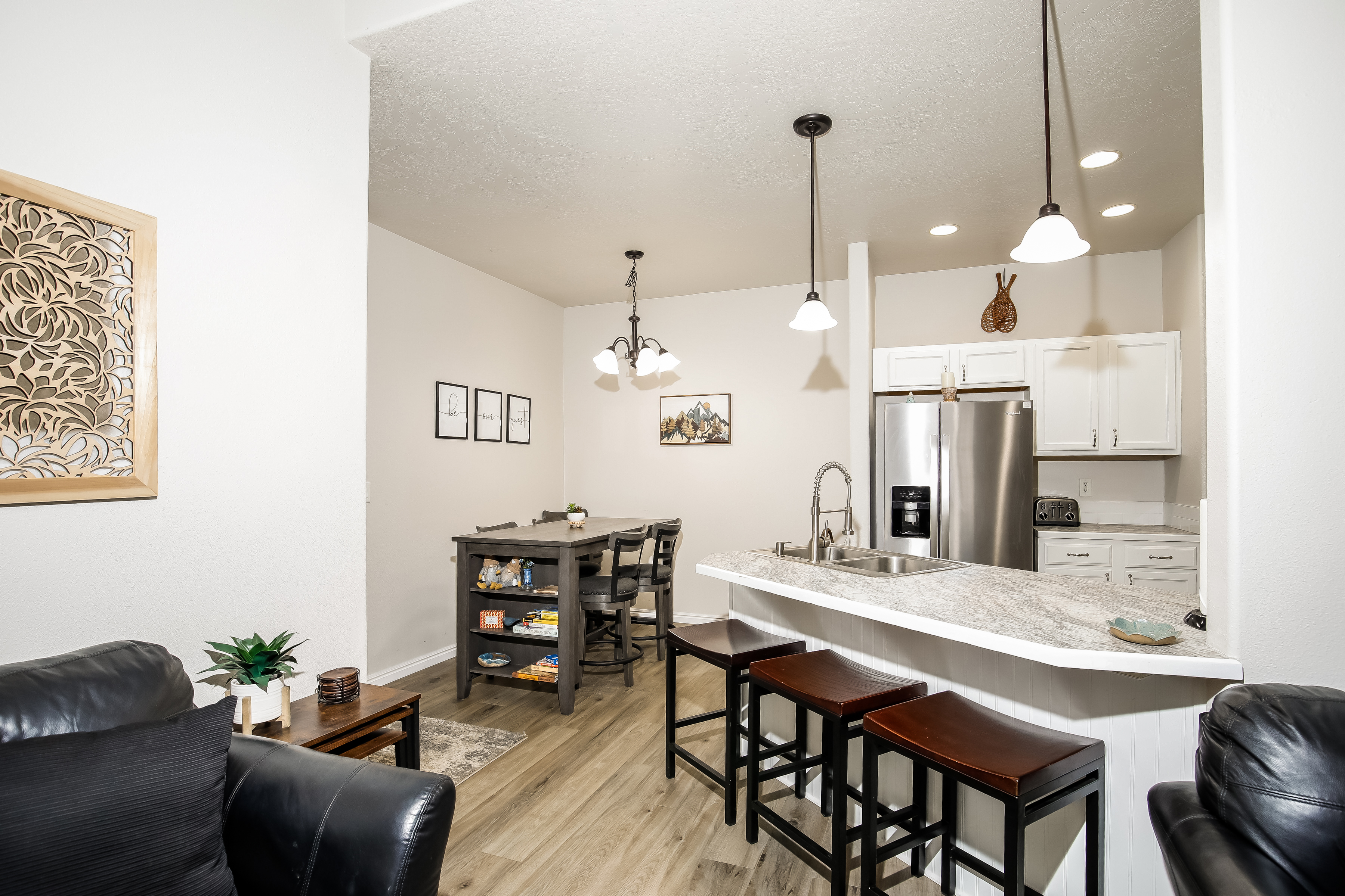 Bright kitchen with breakfast bar, stainless appliances, and game table.