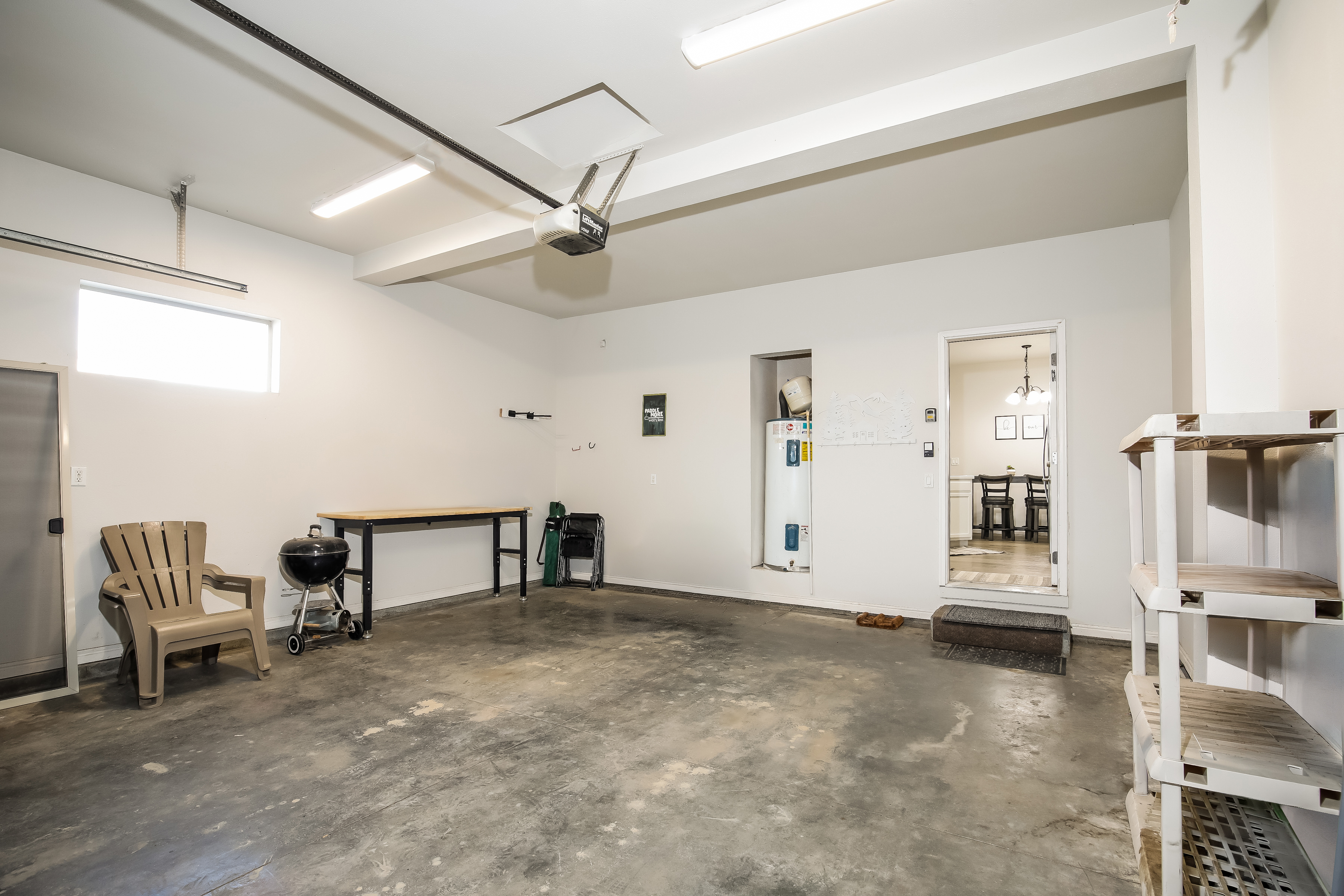 Clean, well-lit garage with workbench, shelving & indoor access